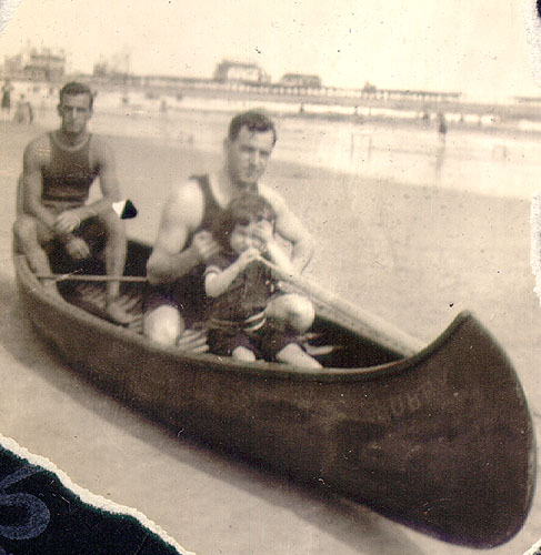 Scanned photo of two adults and a child in a beached canoe.