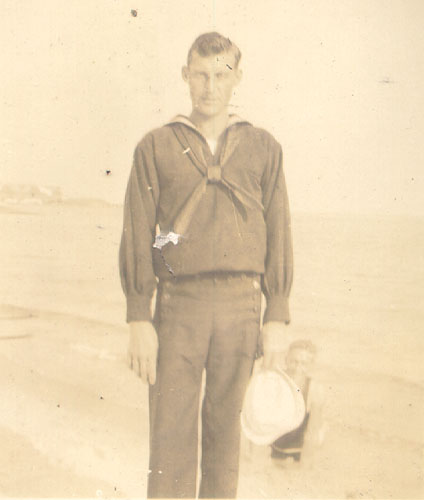 Scanned photo of Hugh Adams standing on a beach.