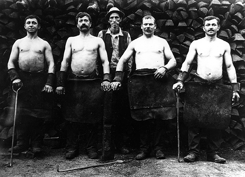 Photo of four muscular, aproned workers.