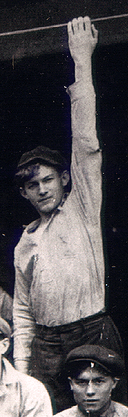 Photo of boy grabbing with his left arm at beam above his 
head.